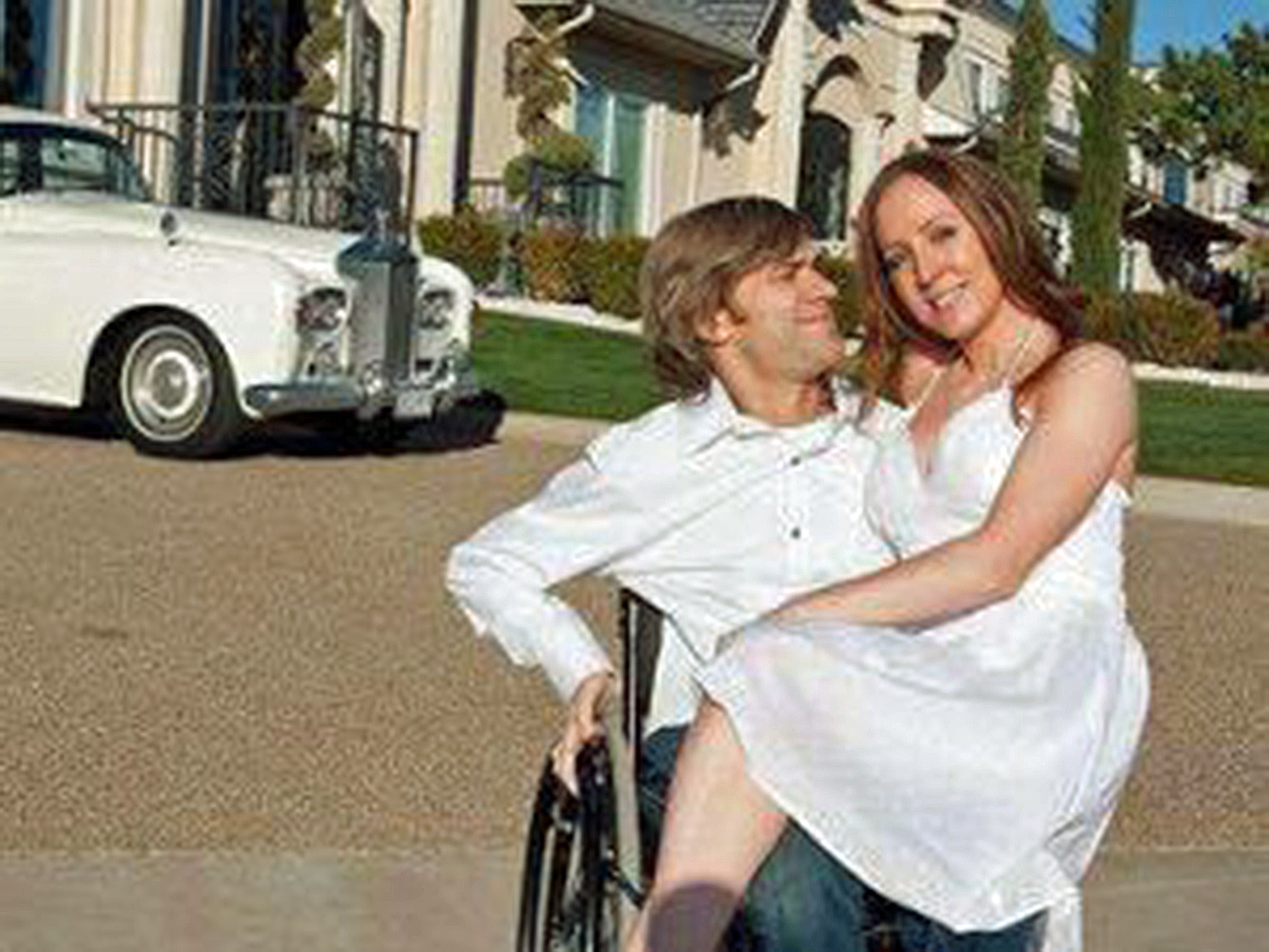 Woman smiling sitting on the lap of a quadriplegic man in a manual wheelchair who is looking at her