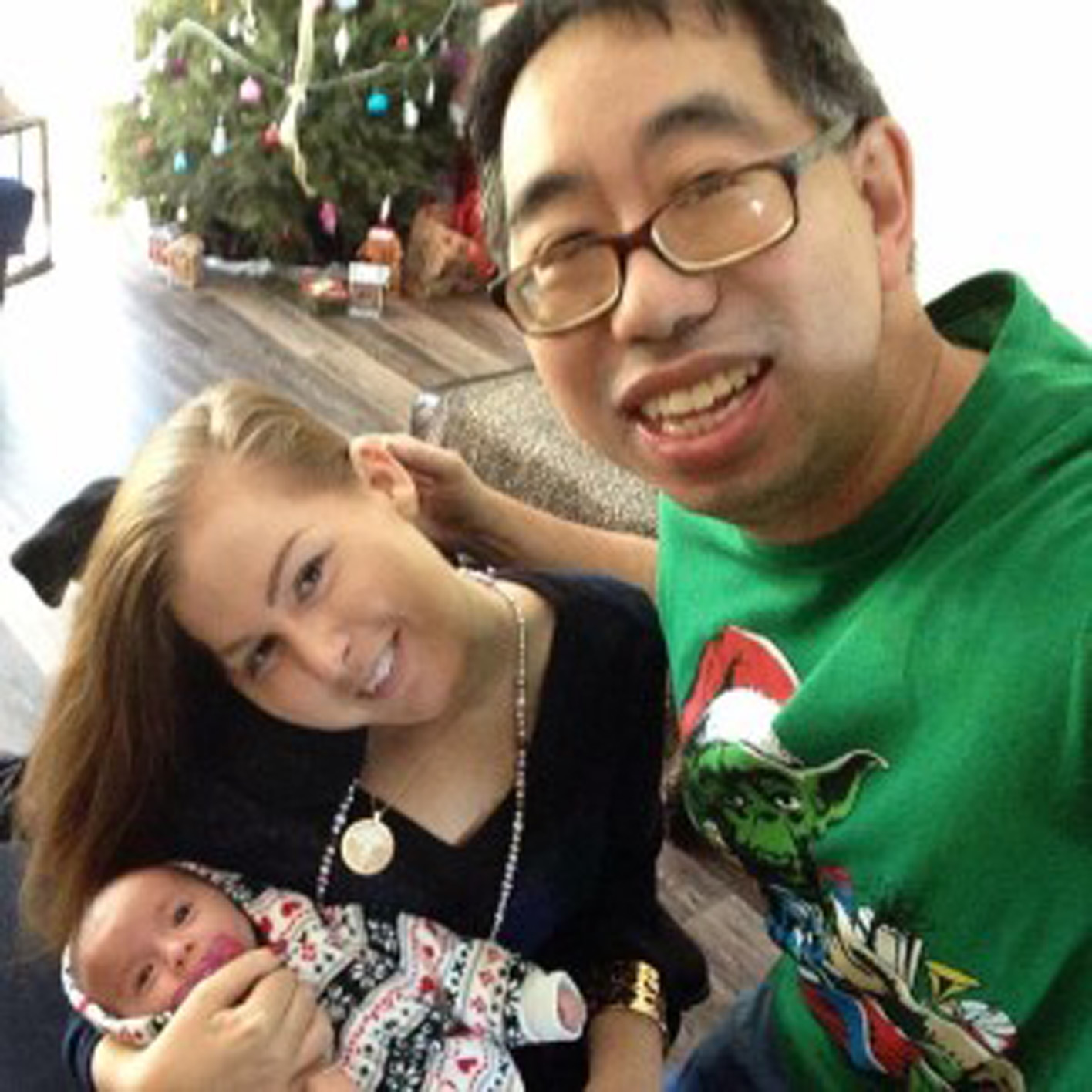 couple holds their newborn daughter and smiles at the camera