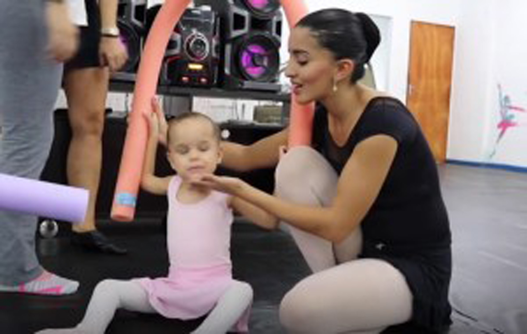 a ballet instructor is teaching a young ballerina