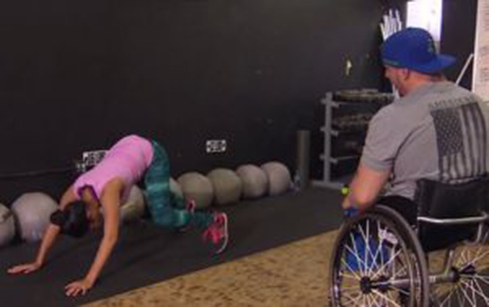 man in manual wheelchair training a woman exercising on the floor