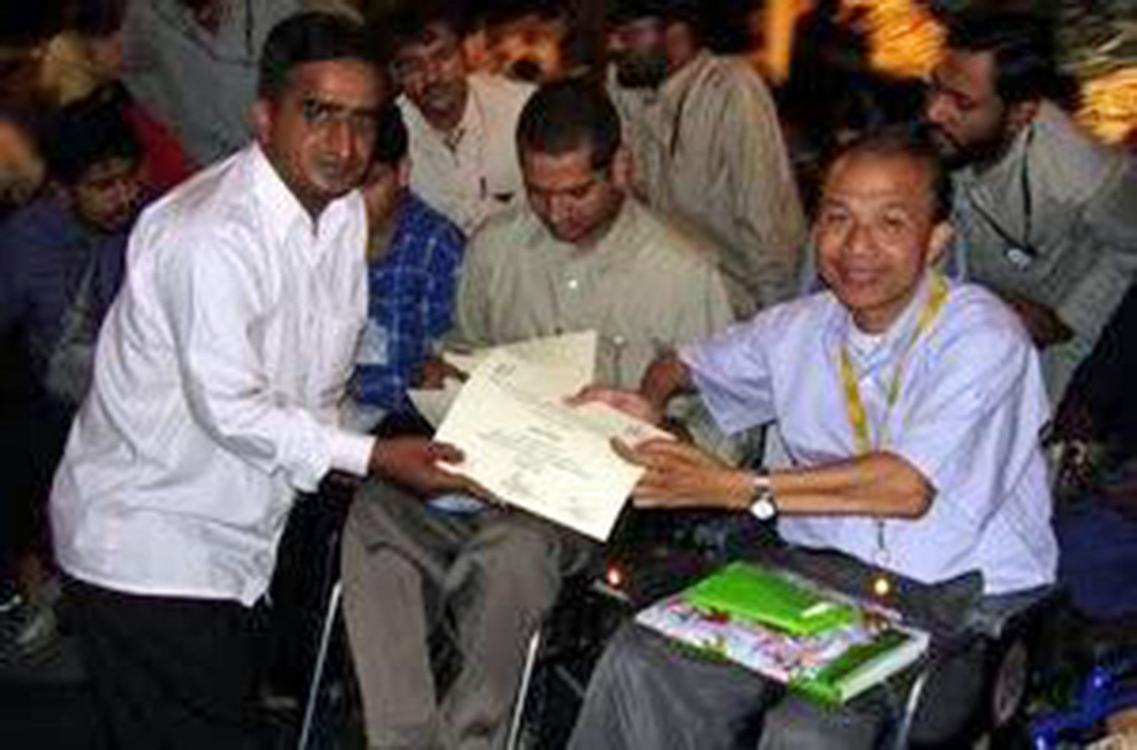 two men in wheelchair with a third man kneeling next to them