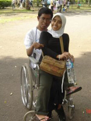 a man in a manual wheelchair with a woman sitting on his lap