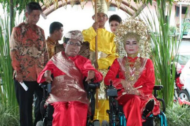 a man and woman with power wheelchairs in wedding attire from indonesia