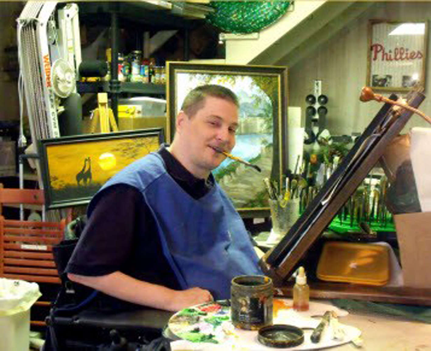 quadriplegic man painting with a brush in his mouth
