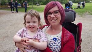Mom with SMA in a power wheelchair holding her toddler