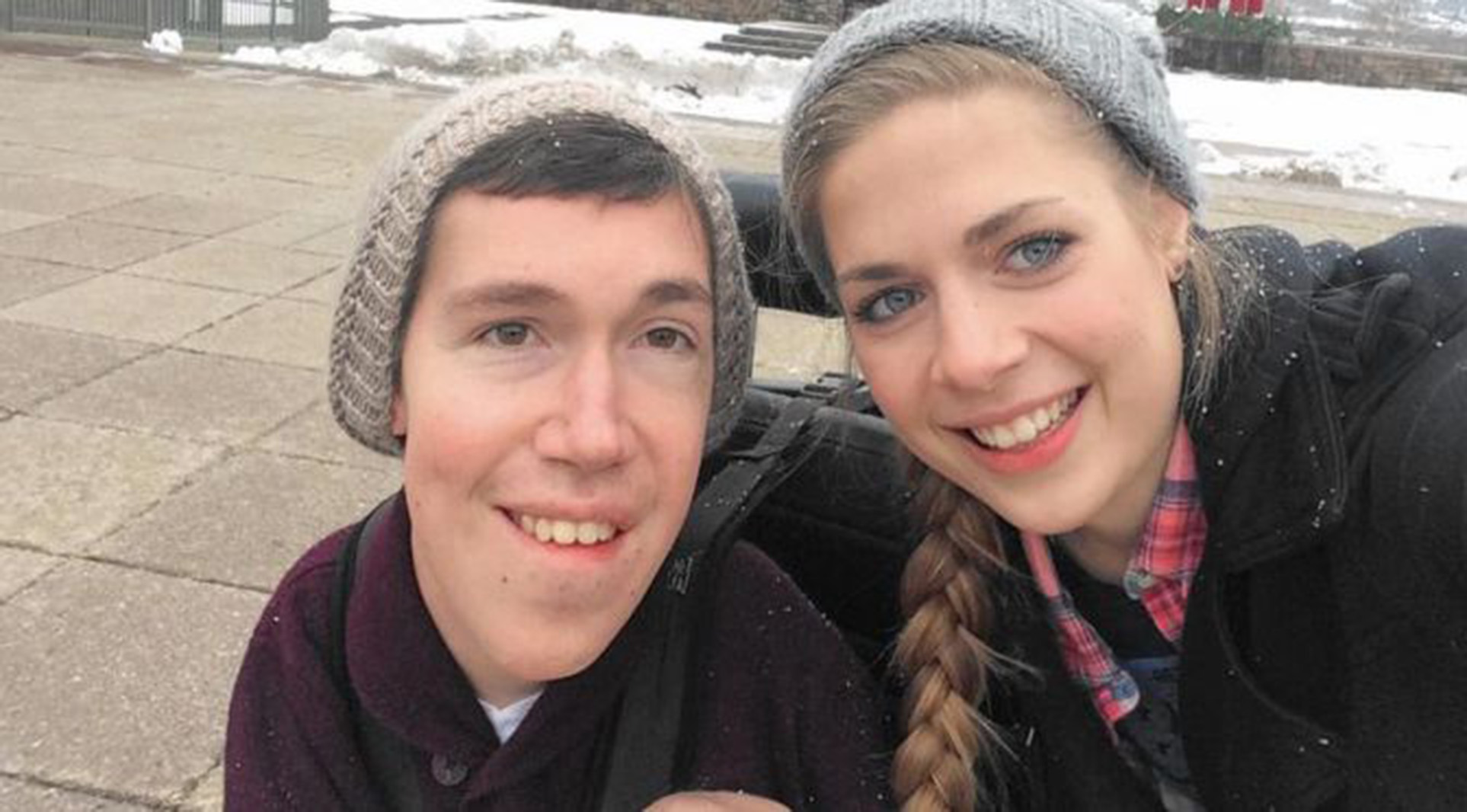 a man in a power wheelchair smiling with his girlfriend
