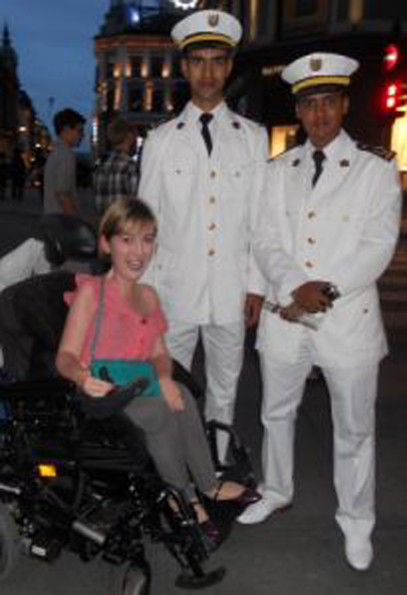 a woman in a power wheelchair with two men in uniform standing next to her
