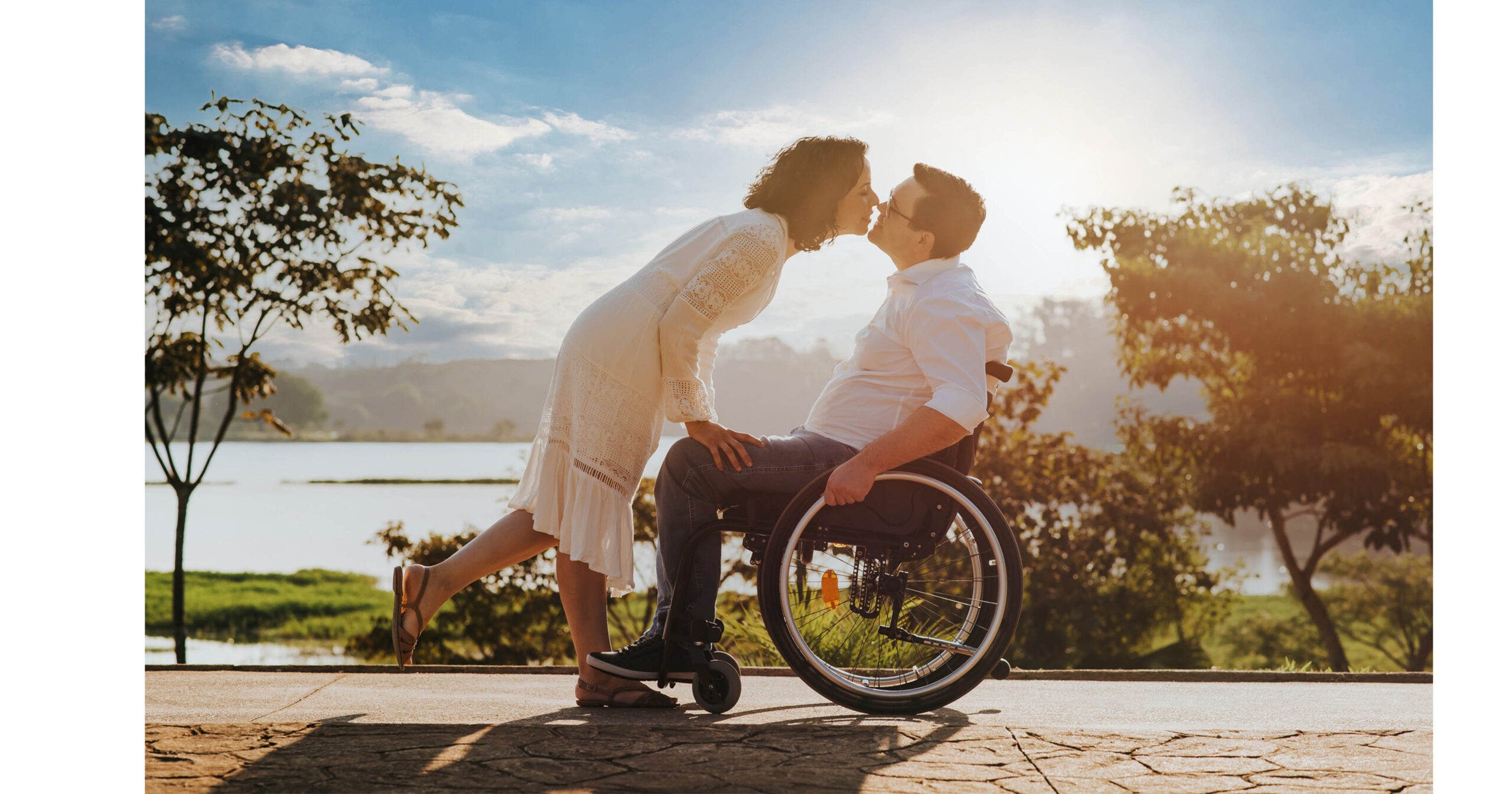 A woman bends over to kiss her male lover, a wheelchair user.