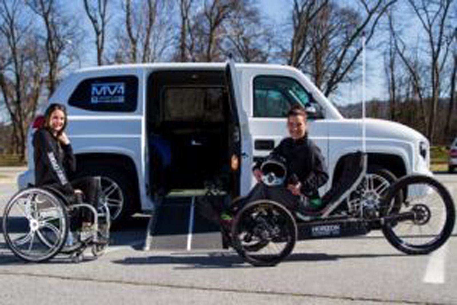 two women in wheelchairs in front of a van