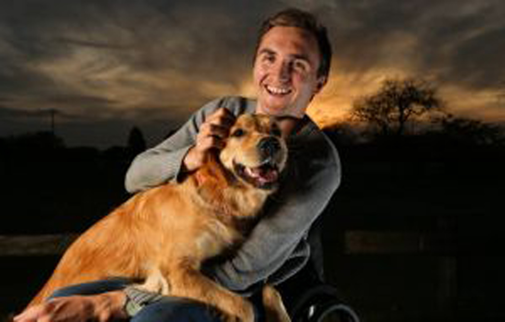 man in a wheelchair holds a dog on his lap