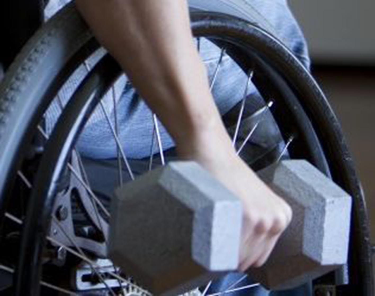 Man in a manual wheelchair holding a dumbell