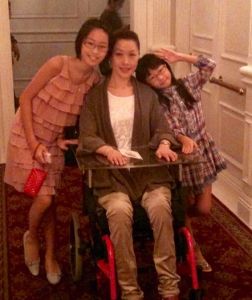 Quadriplegic mom in a manual wheelchair with her two daughters standing at her side
