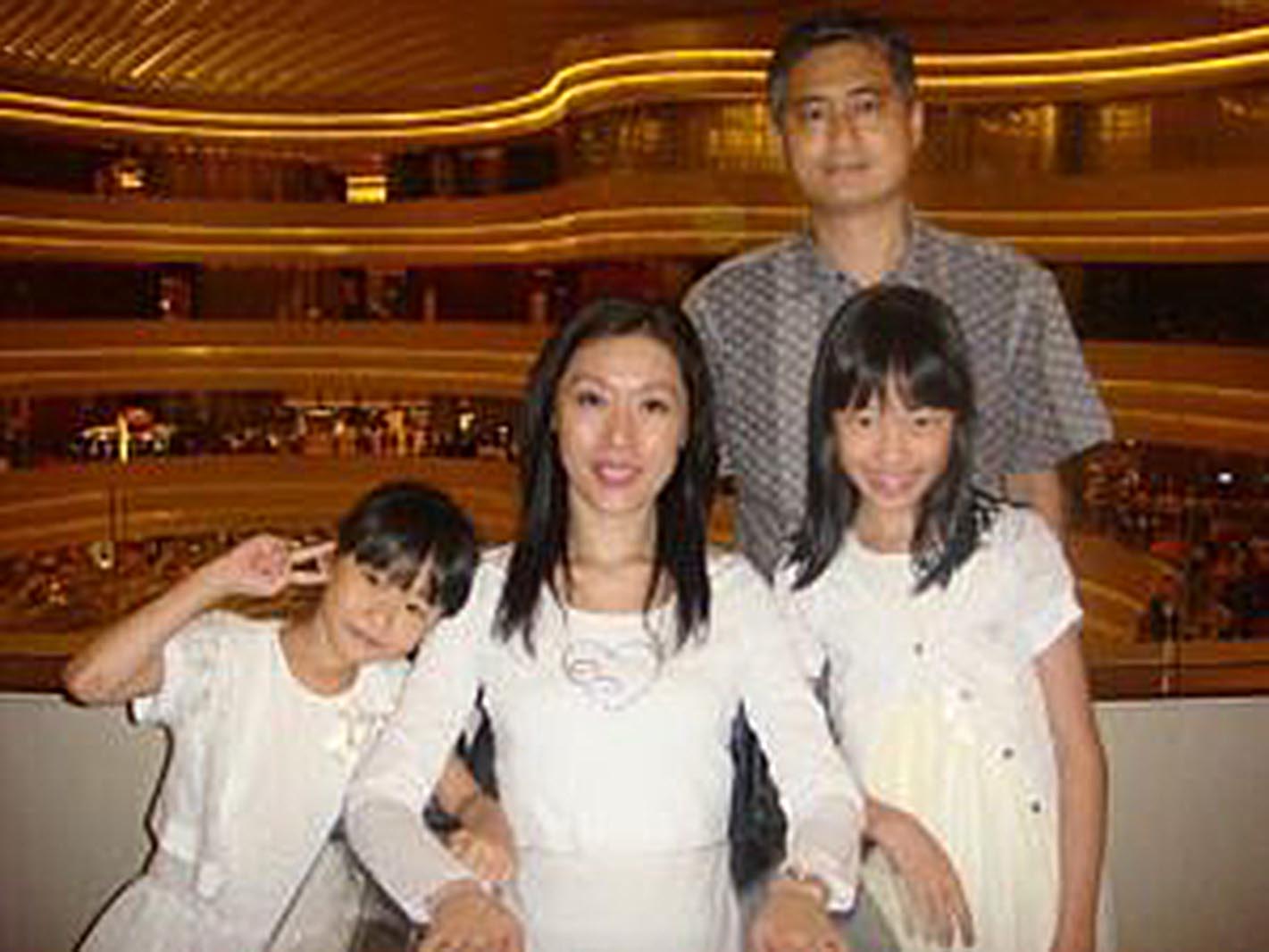 Quadriplegic mom is between her two young daughters and her husband is standing behind them