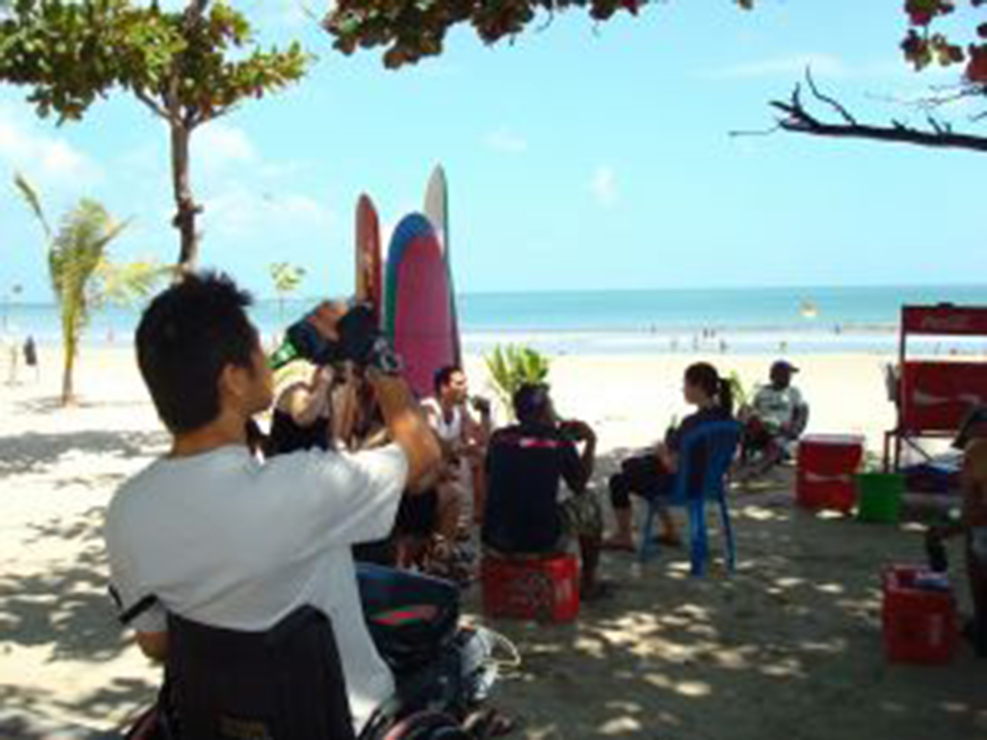 Man in a wheelchair on a beach drinking a beer