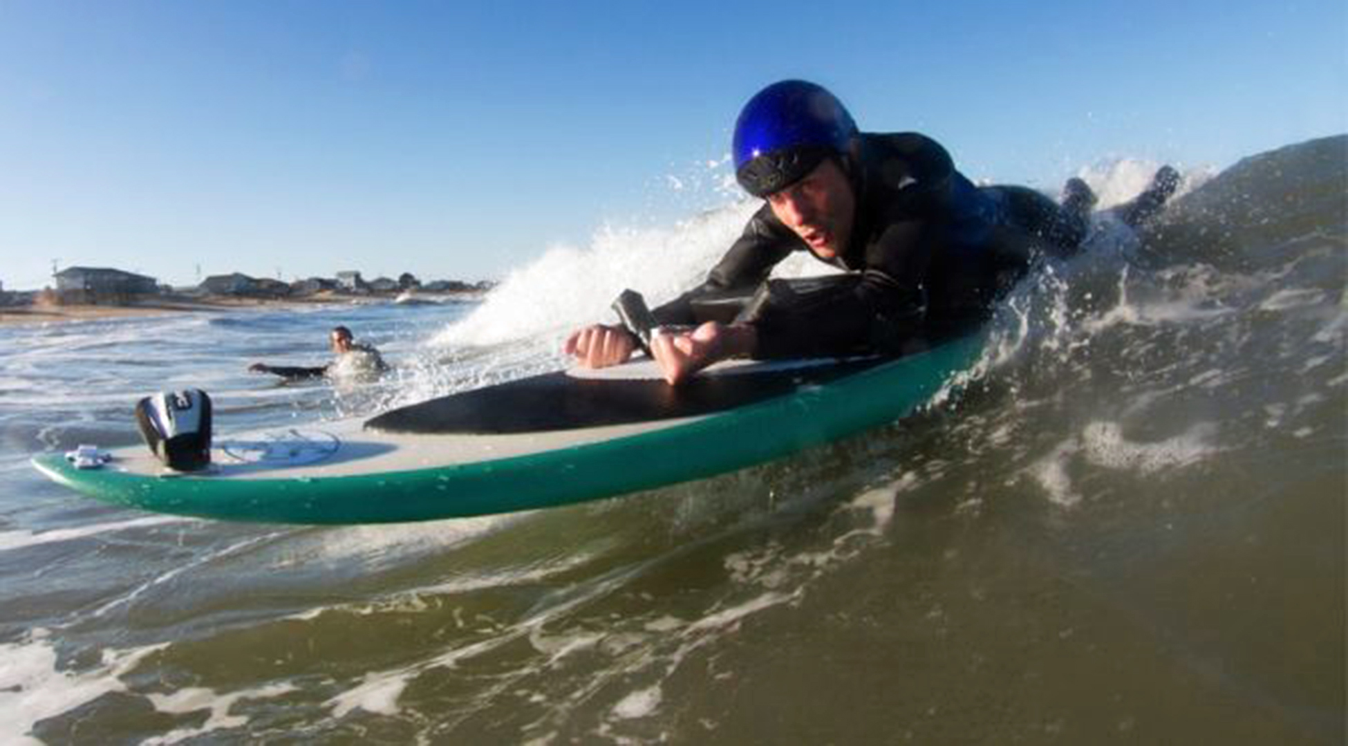 Quadriplegic man laying face down on a surfboard riding a wave