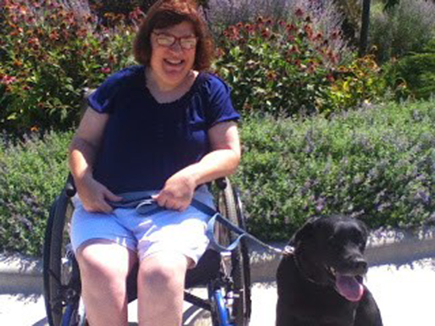 a woman in a manual wheelchair smiling with a dog