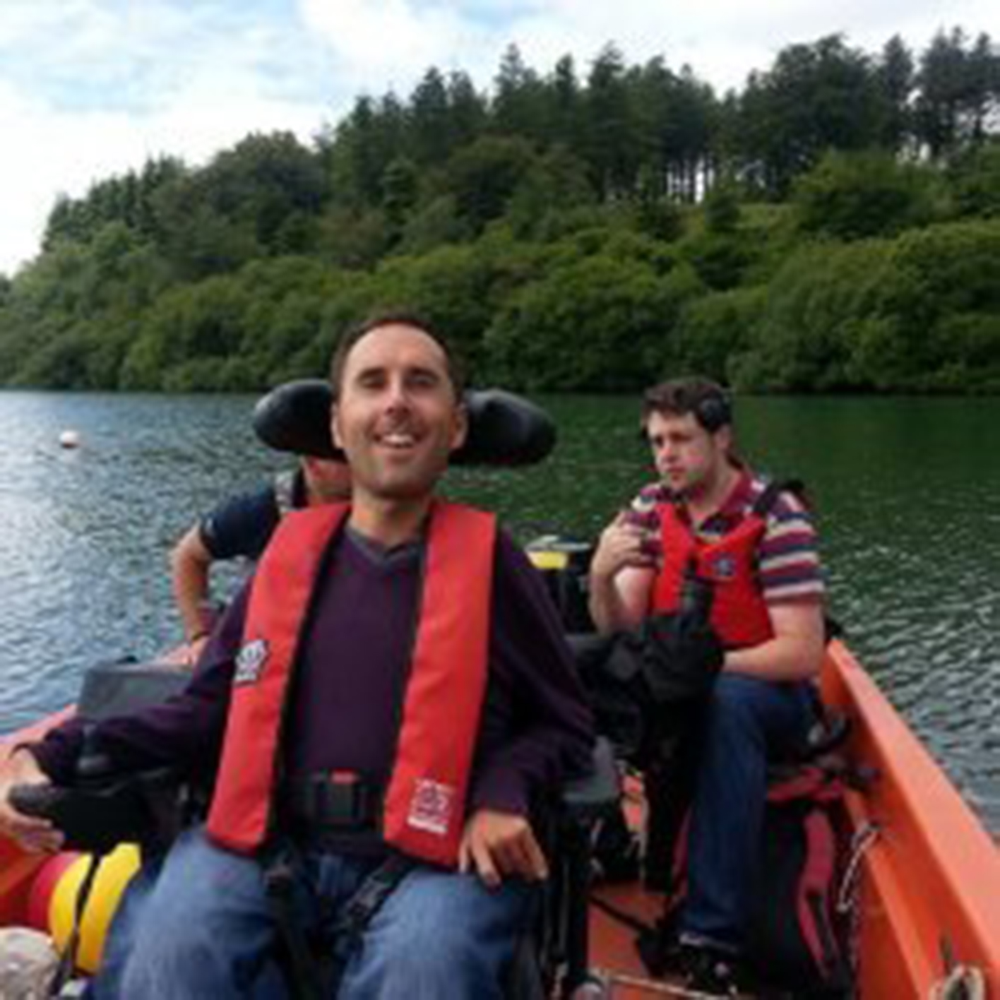 man in a power wheelchair on a boat with another man