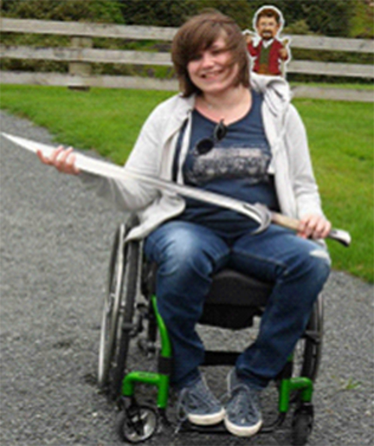 woman in a manual wheelchair holding a sword and smiling