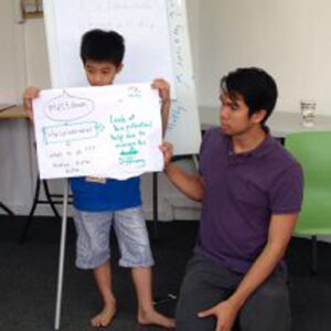 a man kneeling next to a boy holding up a poster