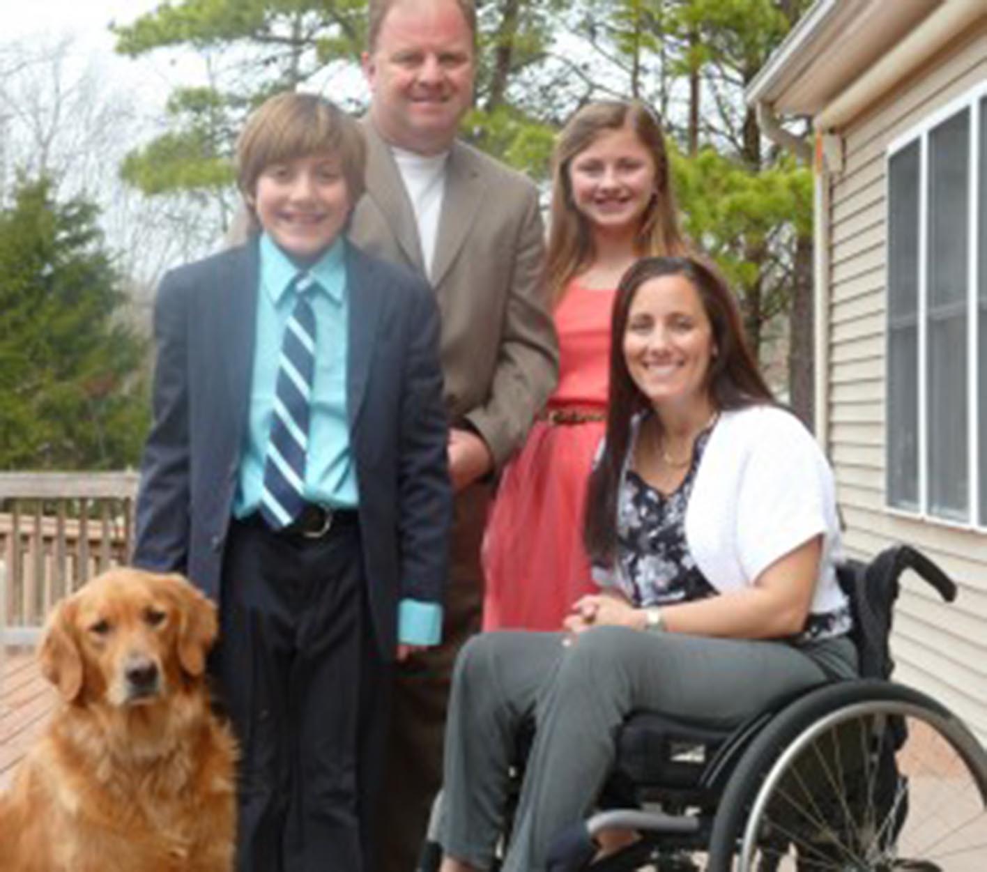 a paraplegic mom in a manual wheelchair next to her husband, son, daughter and their dog