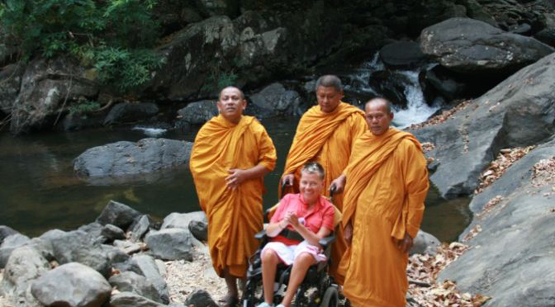 person in power wheelchair with 3 monks in Thailand