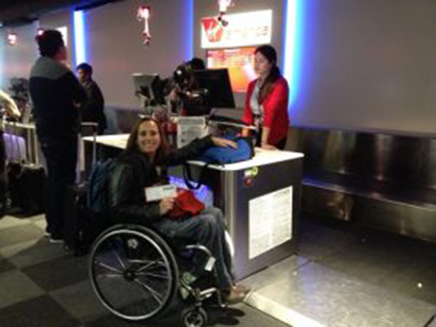 woman in a wheelchair sits next to a check-in counter at an airport