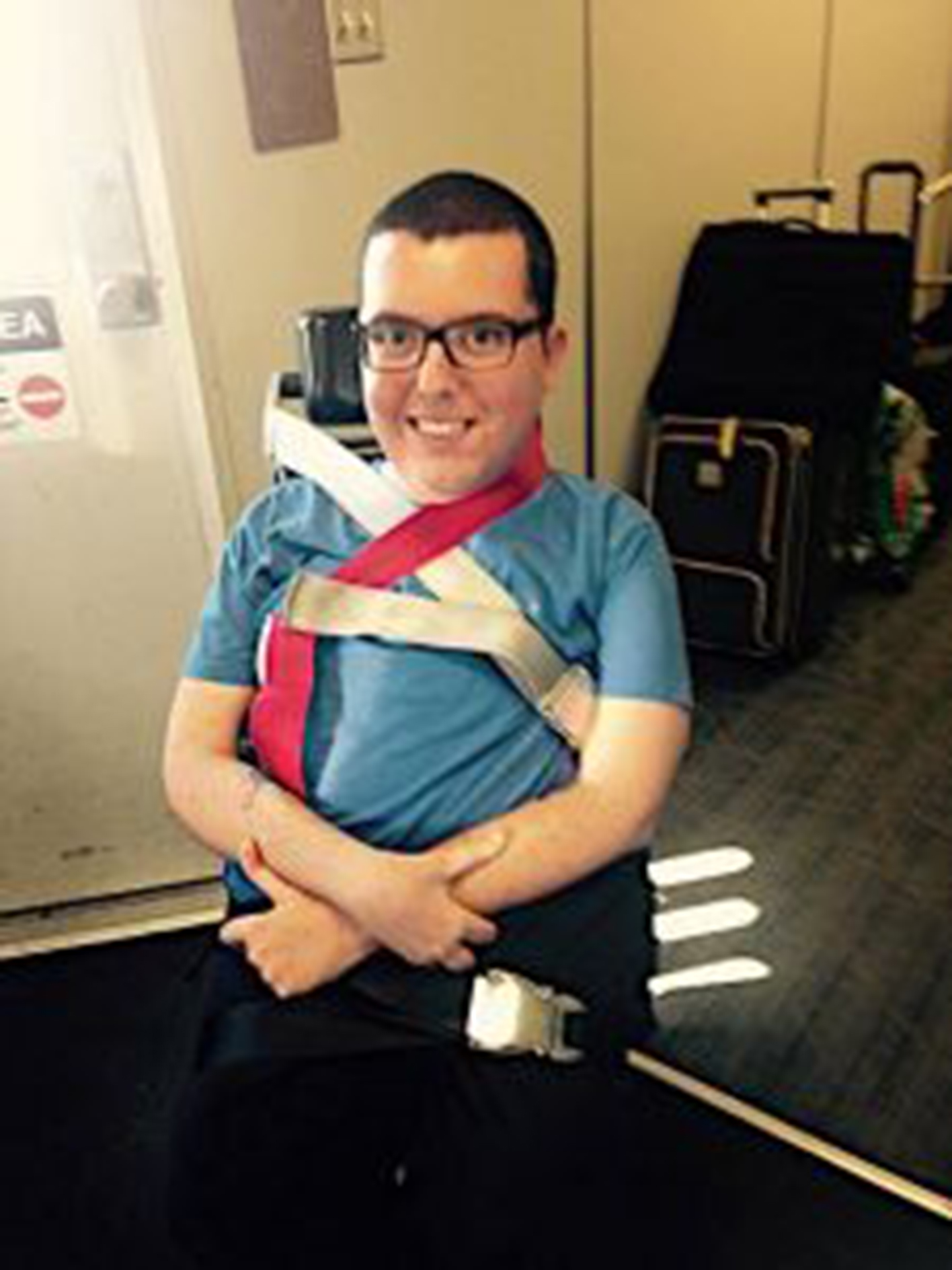 Man sitting on airplane aisle wheelchair smiling