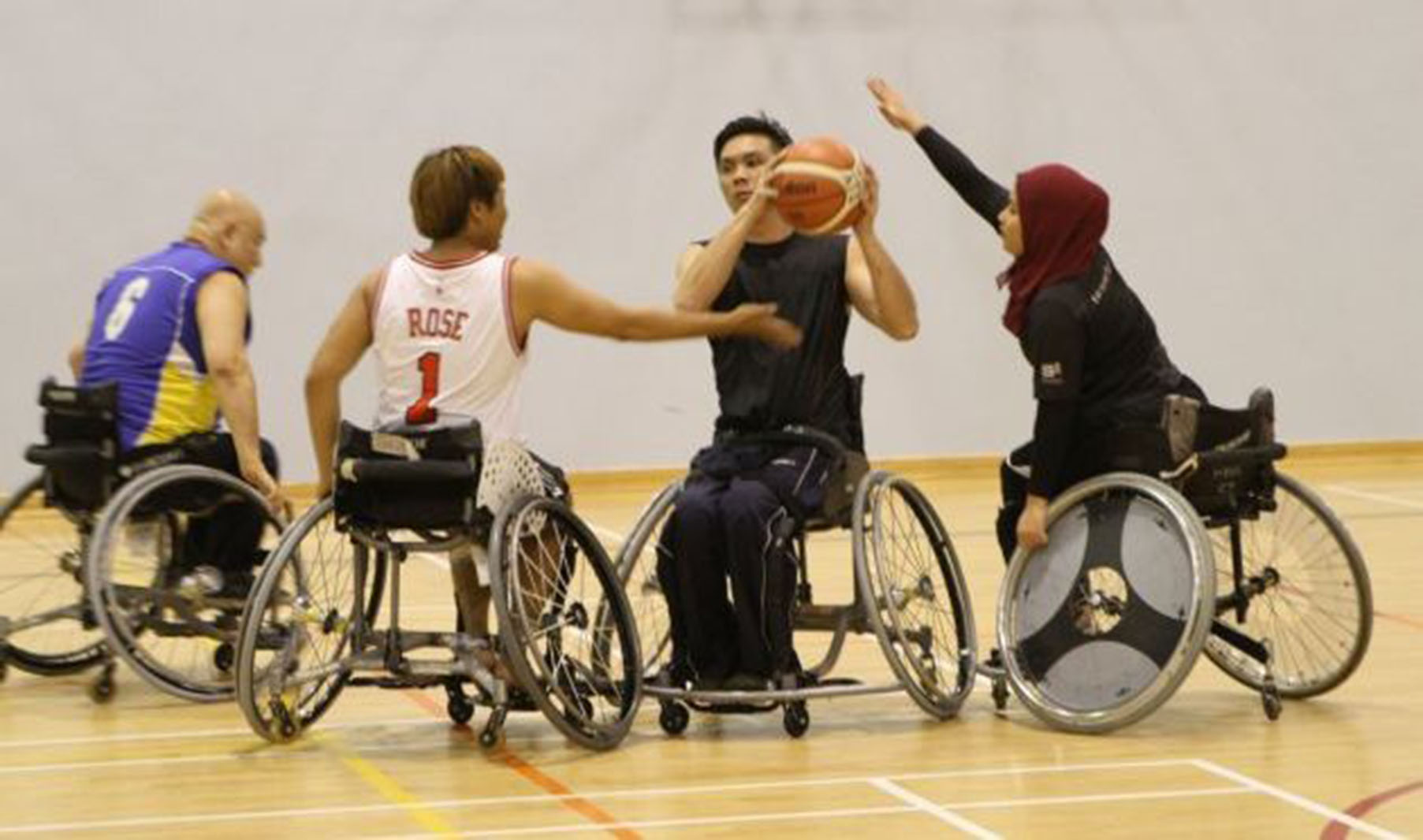 4 men playing wheelchair basketball