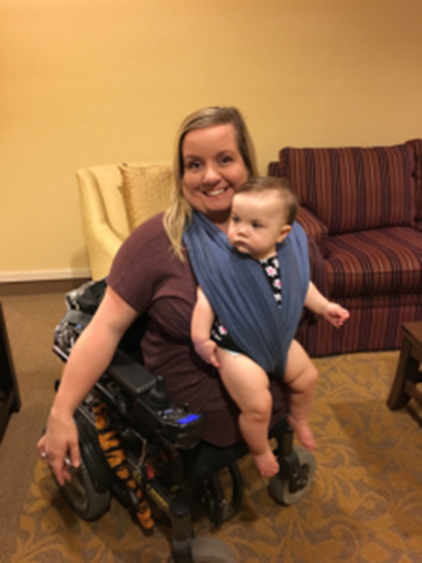 Mom in a power wheelchair with her son strapped to her chest