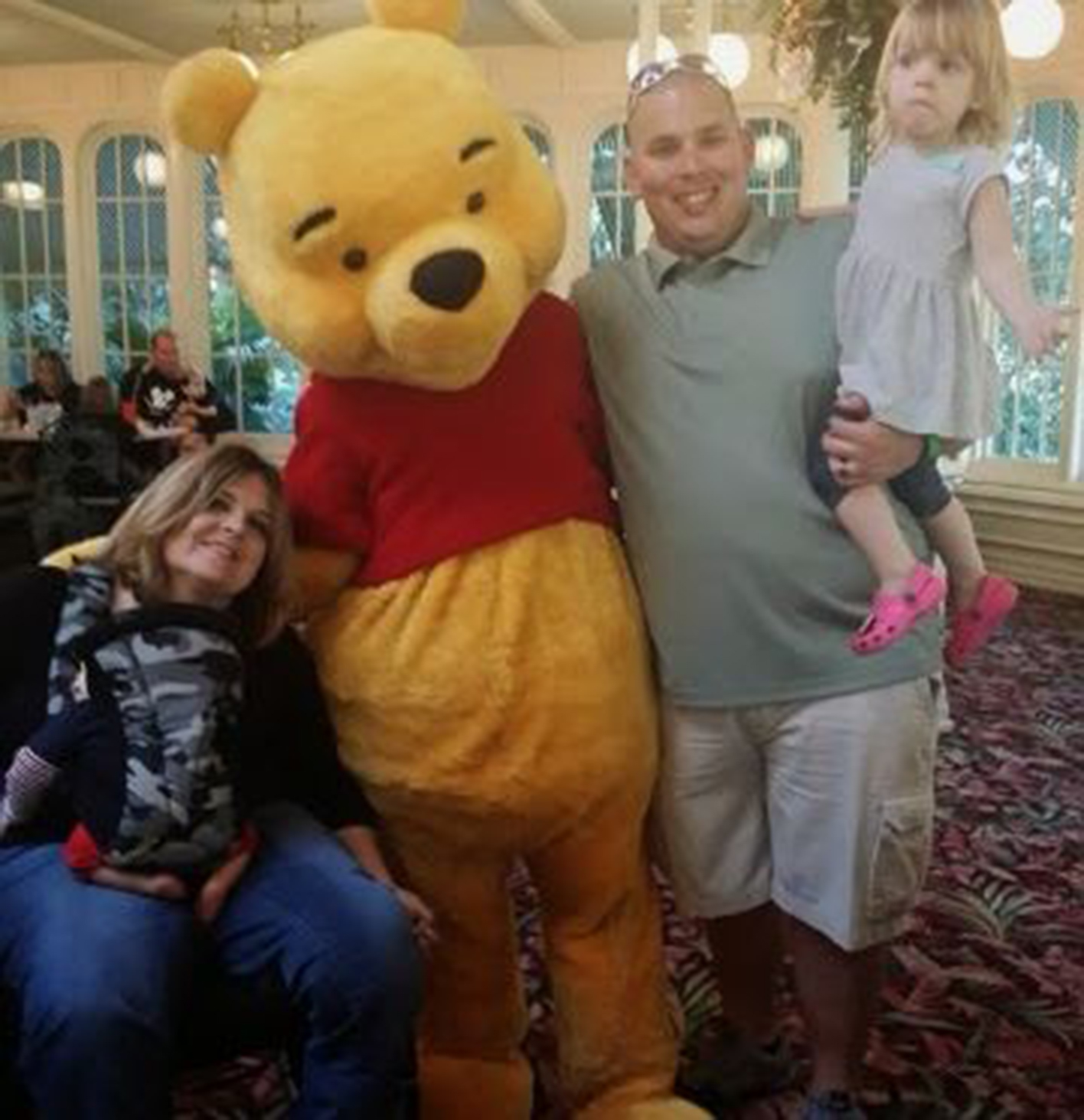 quadriplegic mom, her husband and their daughter posing with Winnie The Pooh
