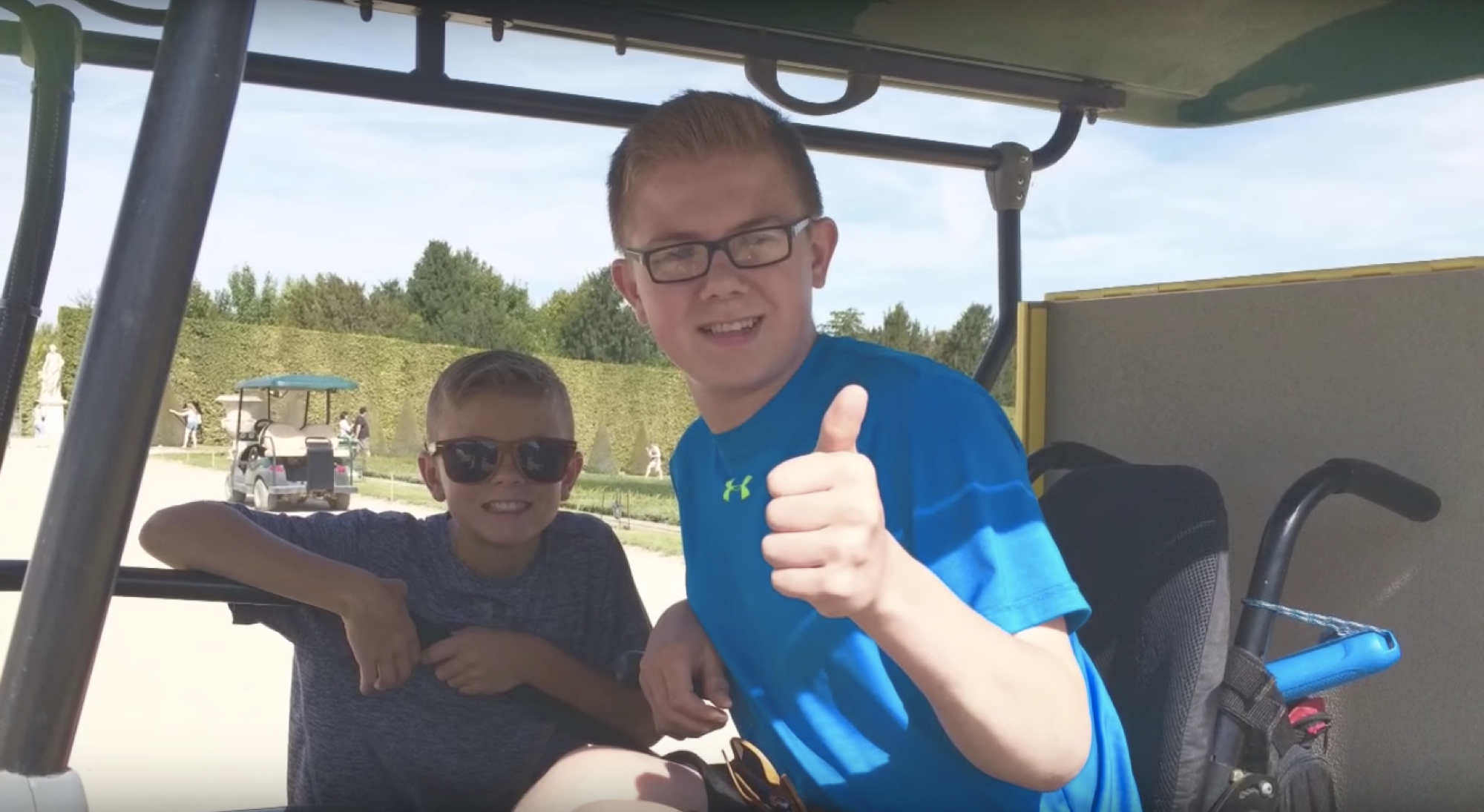 two brothers smiling, one in a wheelchair giving a thumbs up