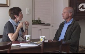 A man and woman seated at a table looking at each other