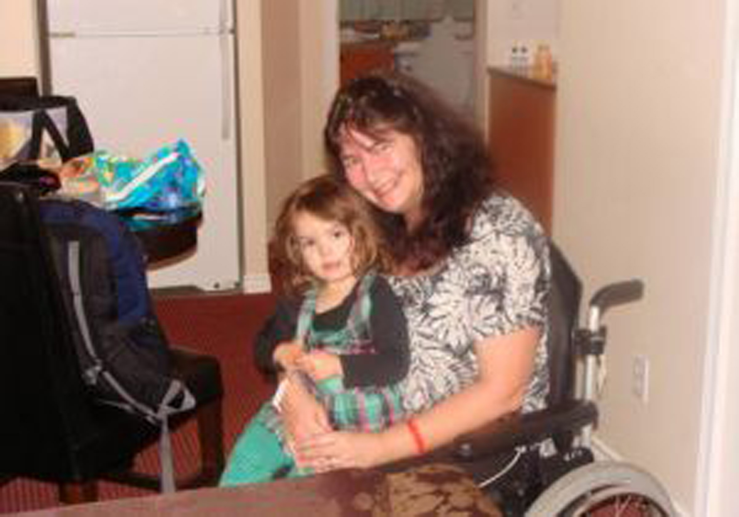 woman in a wheelchair holds a young girl on her lap