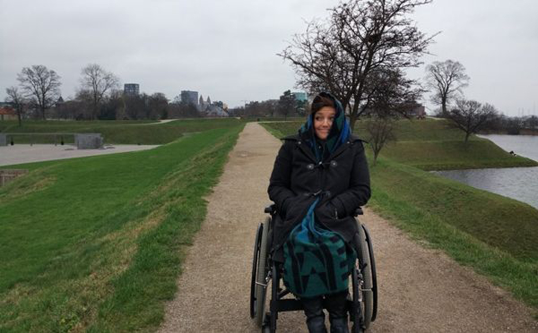 a woman in a manual wheelchair on a path