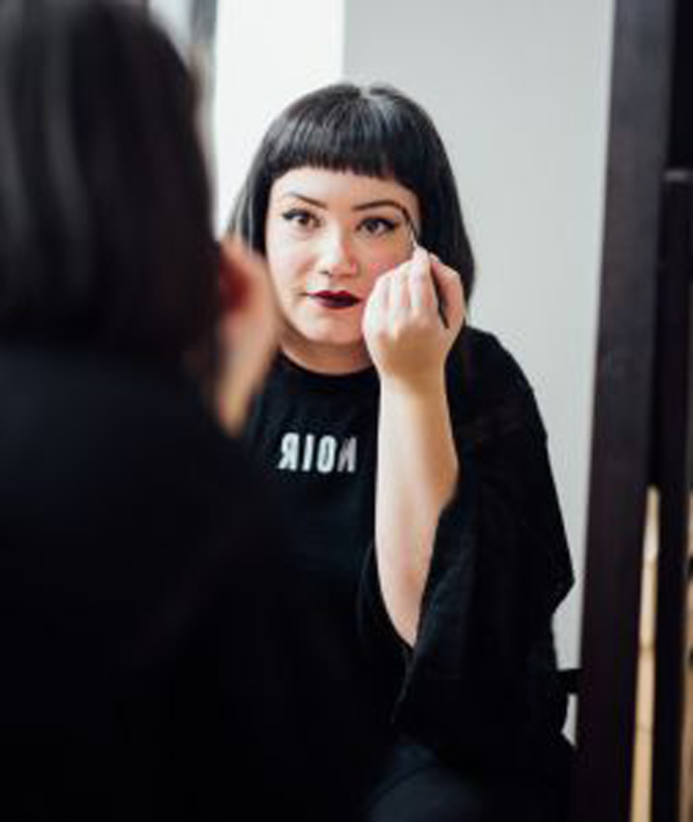 woman looking in the mirror putting on makeup