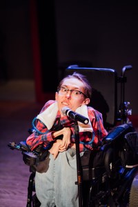 man in a power wheelchair at a microphone