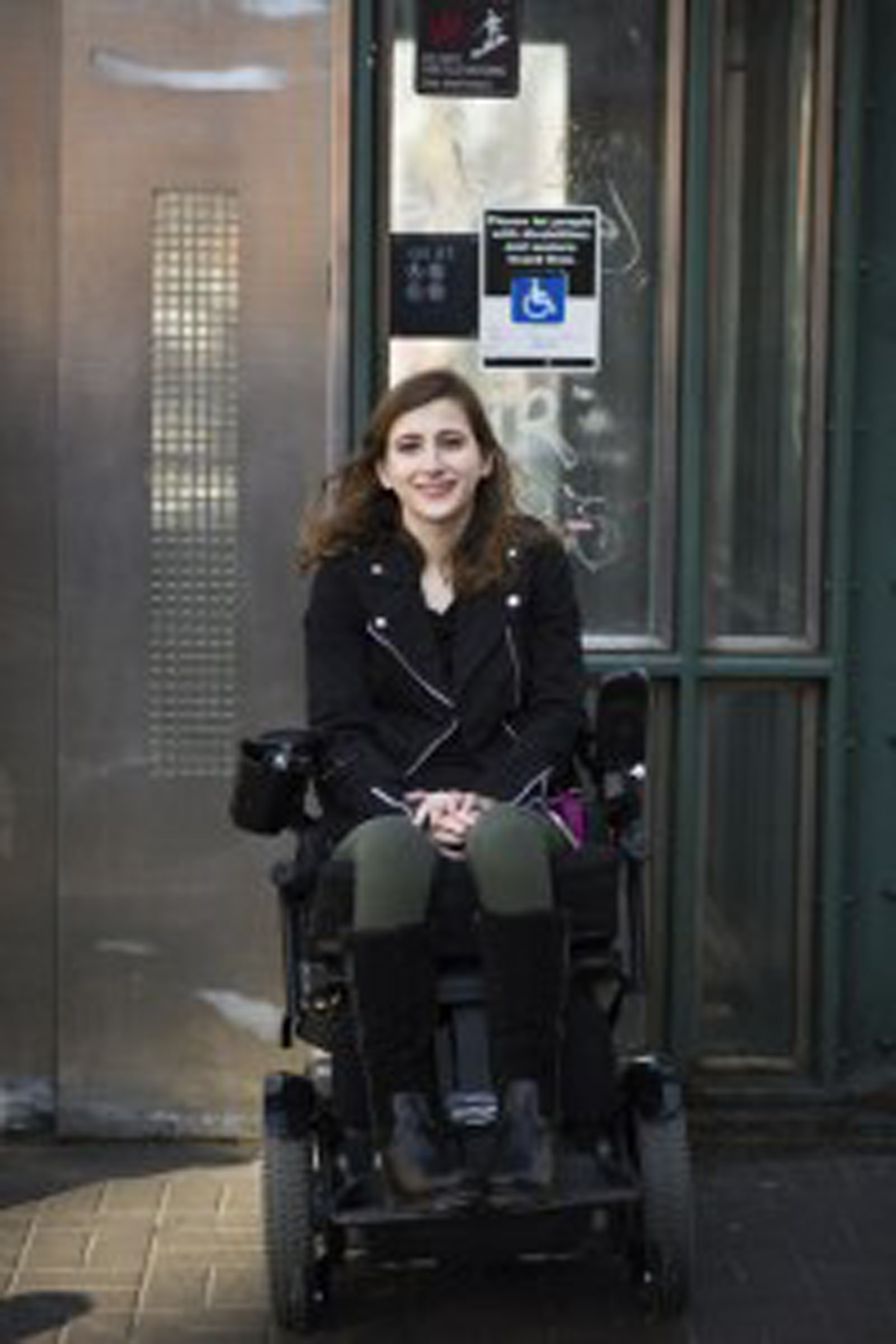 a woman in a power wheelchair in front of an elevator