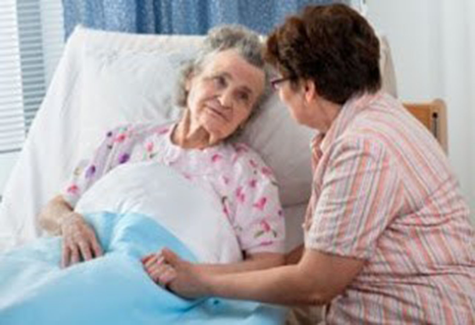 woman lying in a hospital bed with a woman sitting at her side