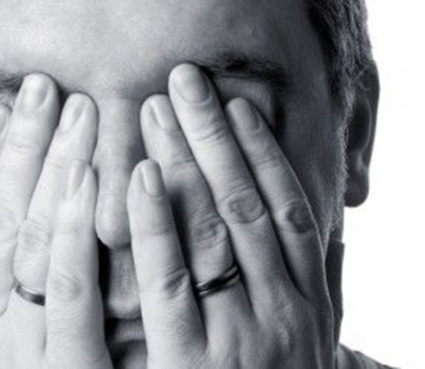 A closeup of a face with their hands covering it.