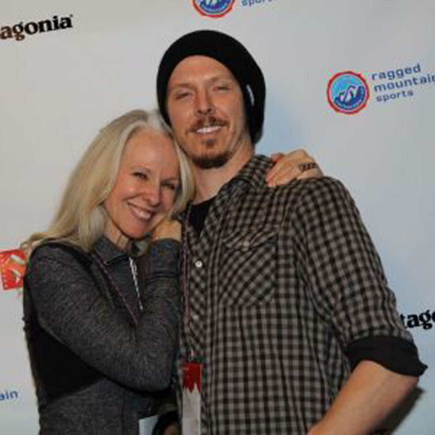 man standing and smiling with his mom next to him with her arms around him
