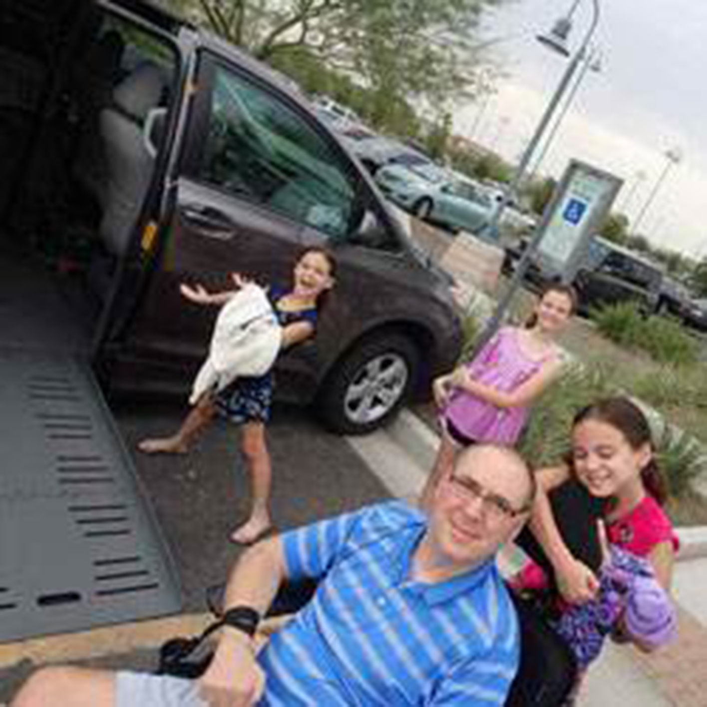 quadriplegic dad outside accessible van with 3 daughters standing around him