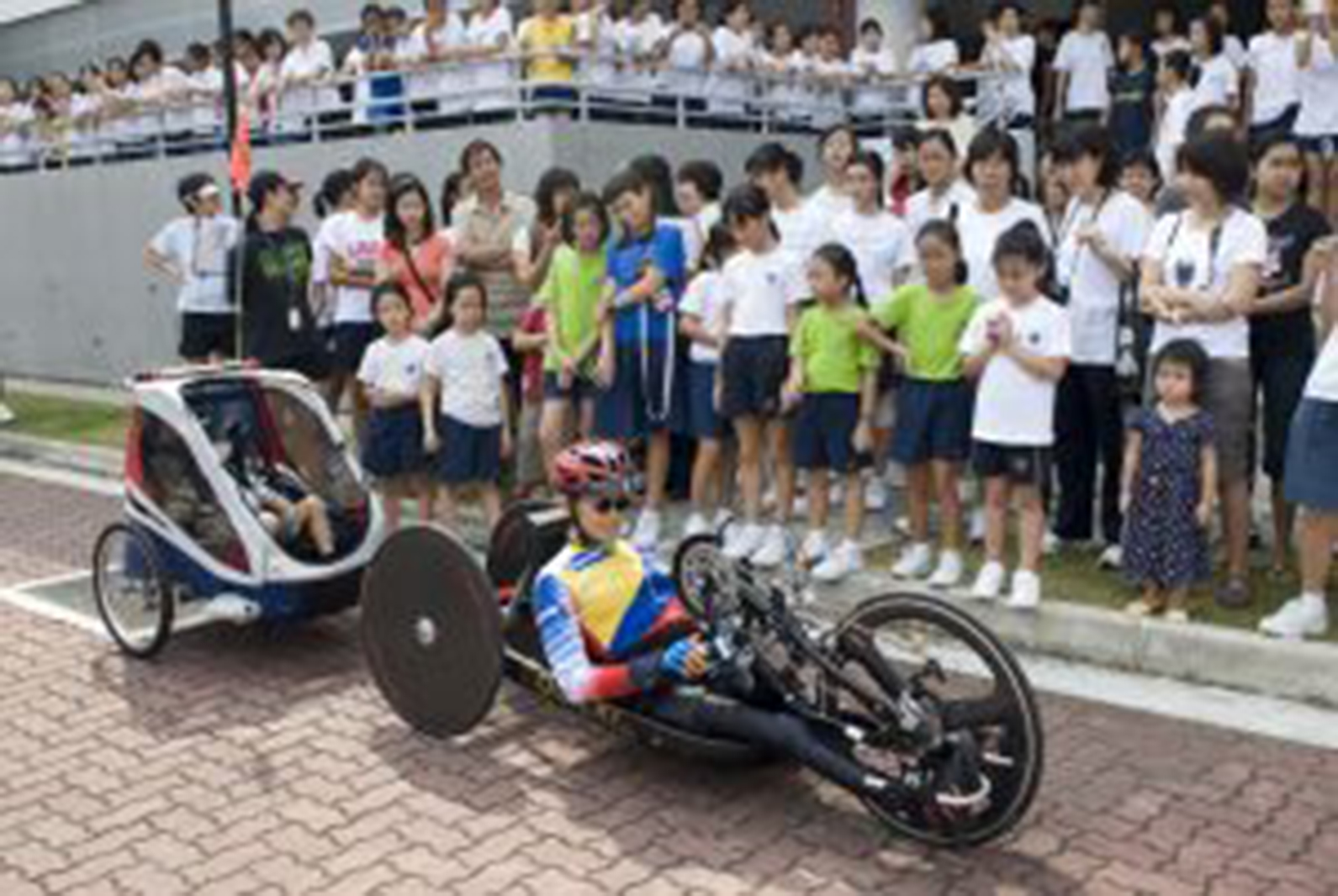 man in a recumbent bike pulling a trailer with a child inside