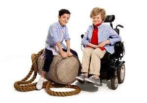 two boys smiling, one in a power wheelchair