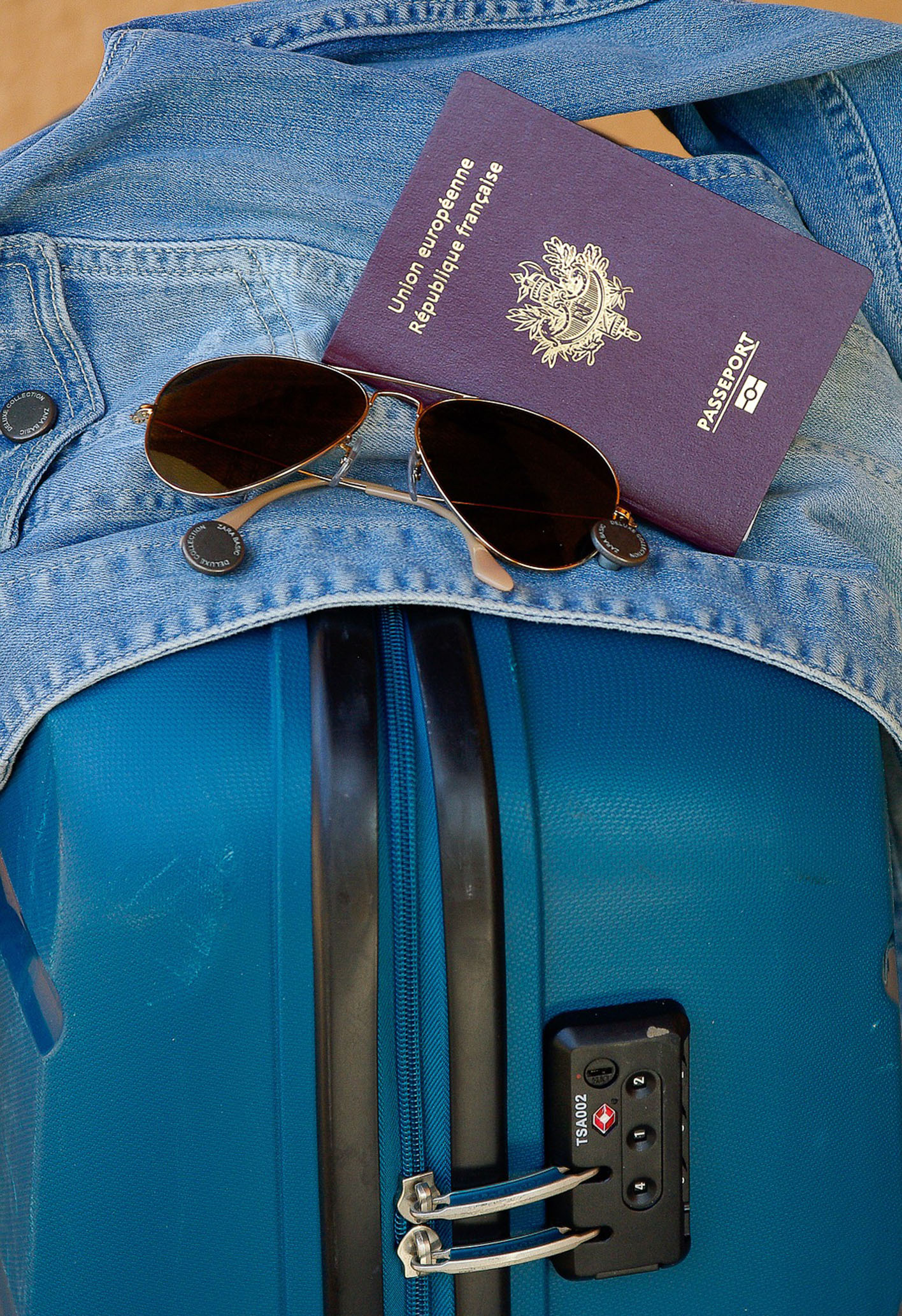 a jacket, sunglasses and passport on top of a suitcase