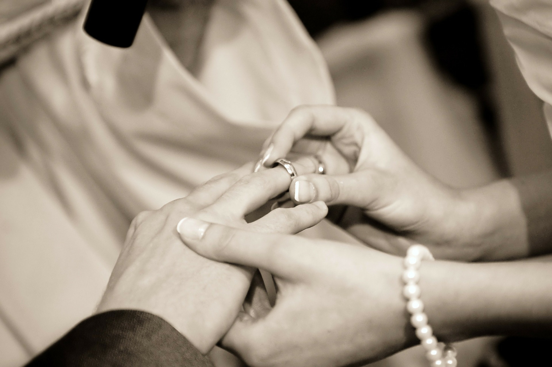 a bride sliding a ring onto a groom's finger