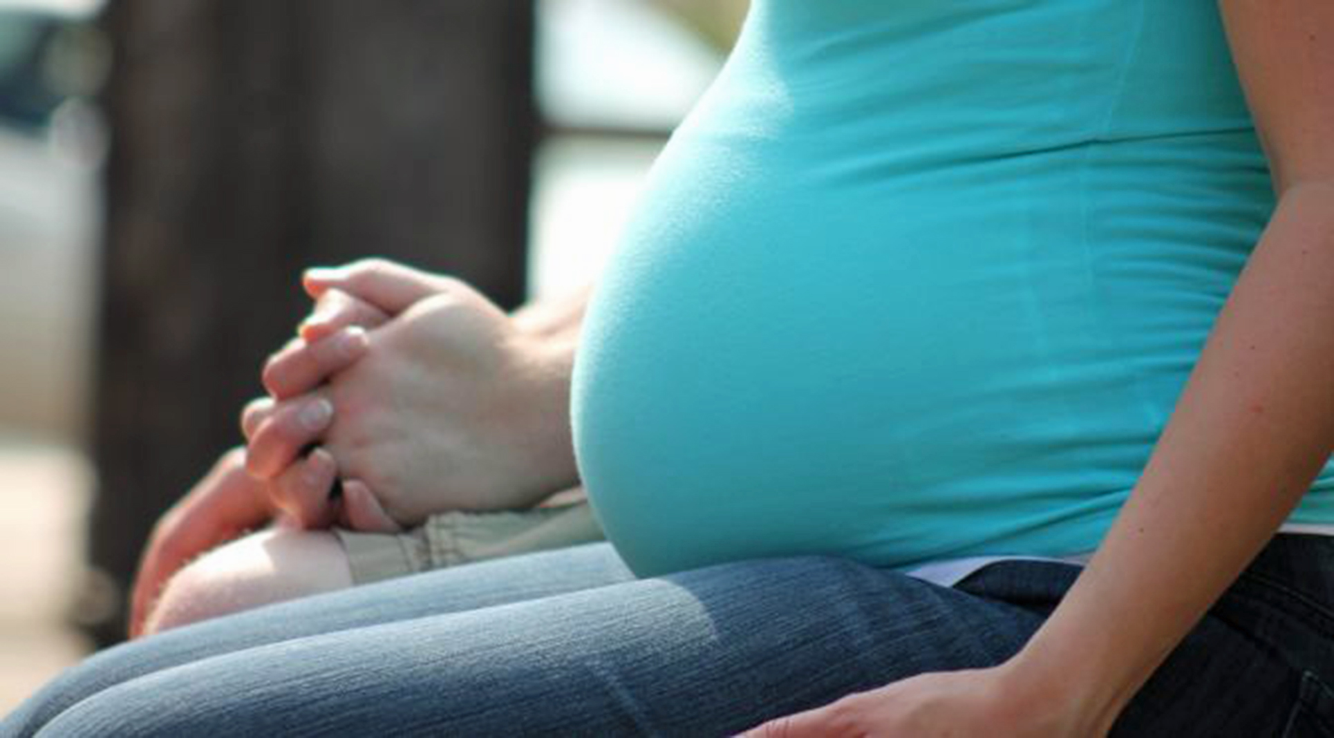 A pregnant woman sitting, only the torso is visible