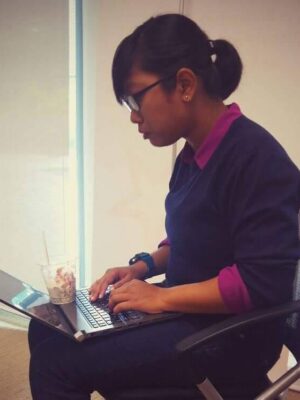 woman sits in an office chair and types on a laptop