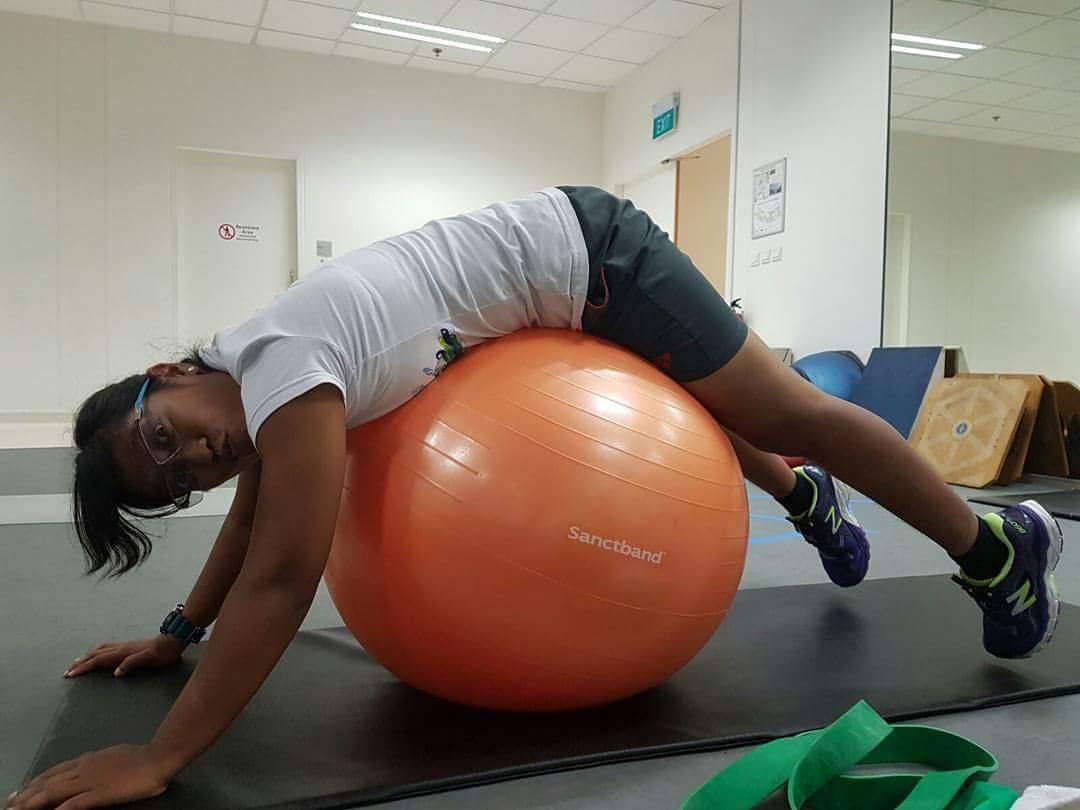 woman stretches on a gym ball