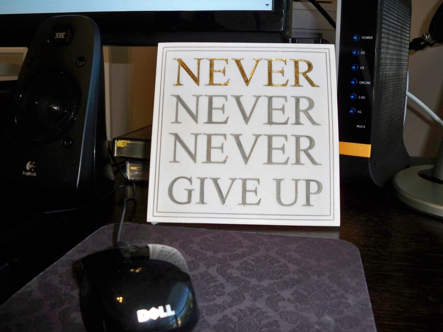 a plaque reading "never, never, never give up" sits on a desk 