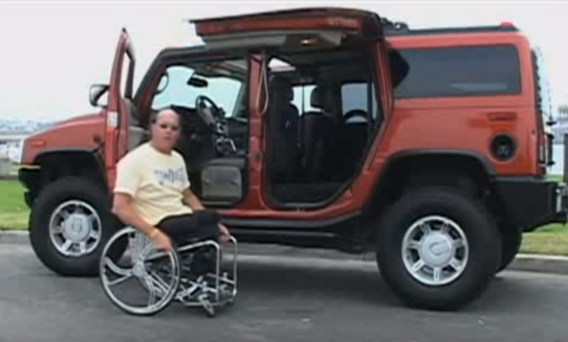 paraplegic man sits in front of his modified vehicle